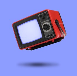 Image of Retro TV set in air on violet blue background