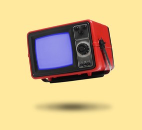 Image of Retro TV set in air on pale orange background