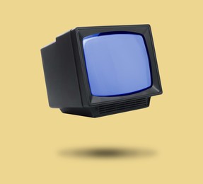 Image of Retro TV set in air on pale orange background