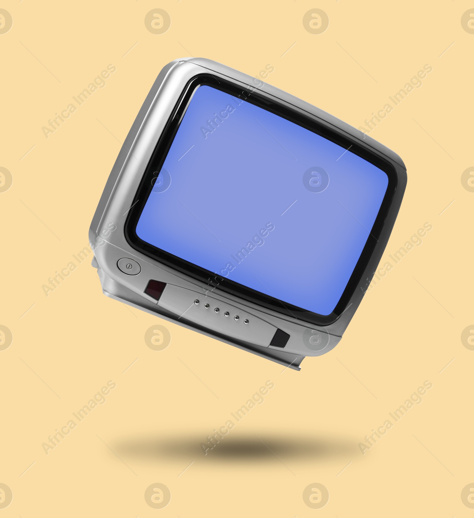 Image of Retro TV set in air on pale orange background