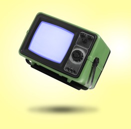 Image of Retro TV set in air on yellow background