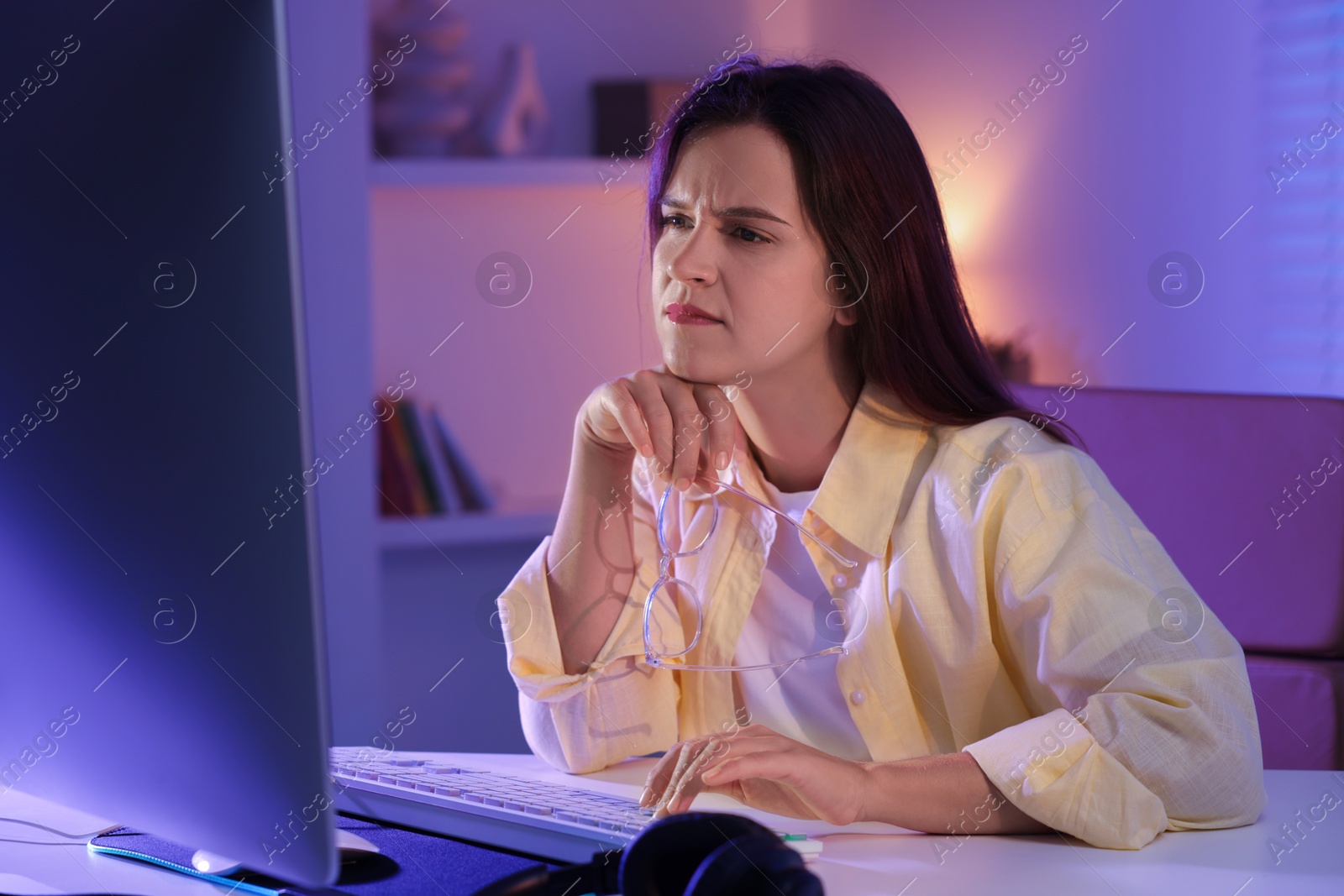 Photo of Woman playing video game with keyboard at table indoors