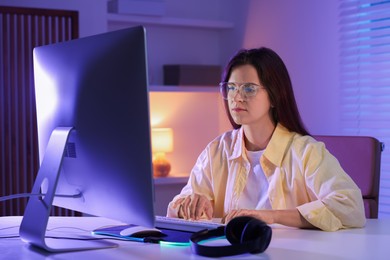 Photo of Woman playing video game with keyboard at table indoors