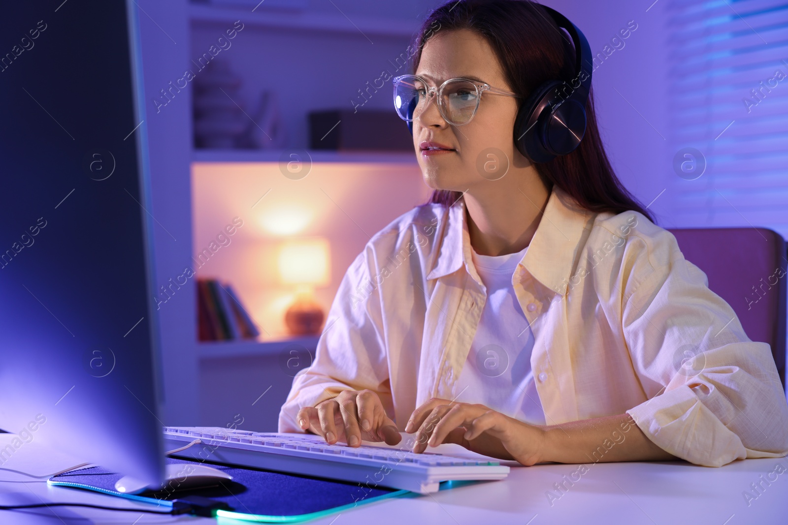 Photo of Woman playing video game with keyboard at table indoors