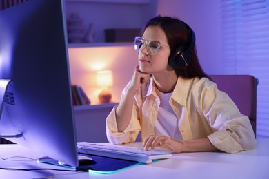 Photo of Woman playing video game with keyboard at table indoors