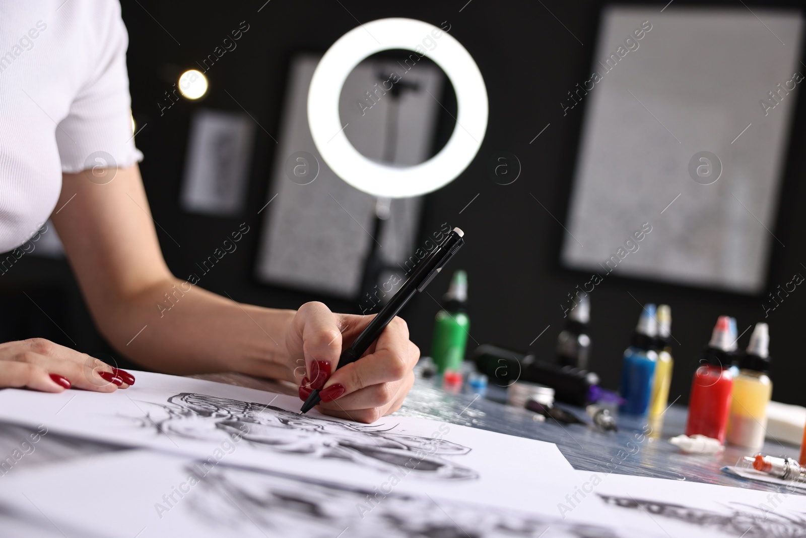 Photo of Tattoo artist drawing sketch at table with supplies in salon, closeup