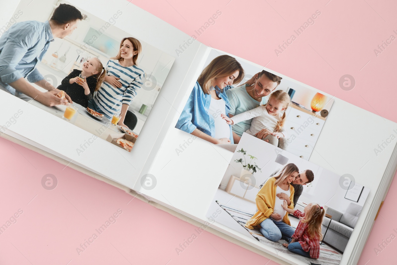 Photo of Open photo album with different photos on pink background, above view