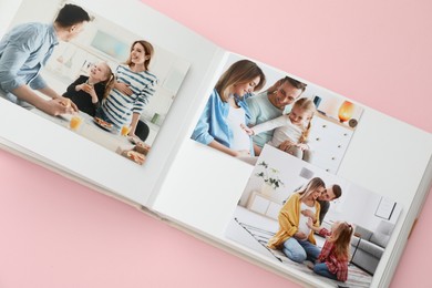 Photo of Open photo album with different photos on pink background, above view