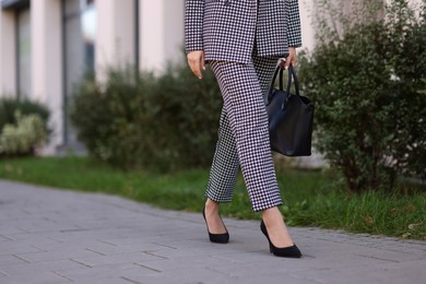 Businesswoman in stylish suit walking at work outdoors, closeup. Space for text