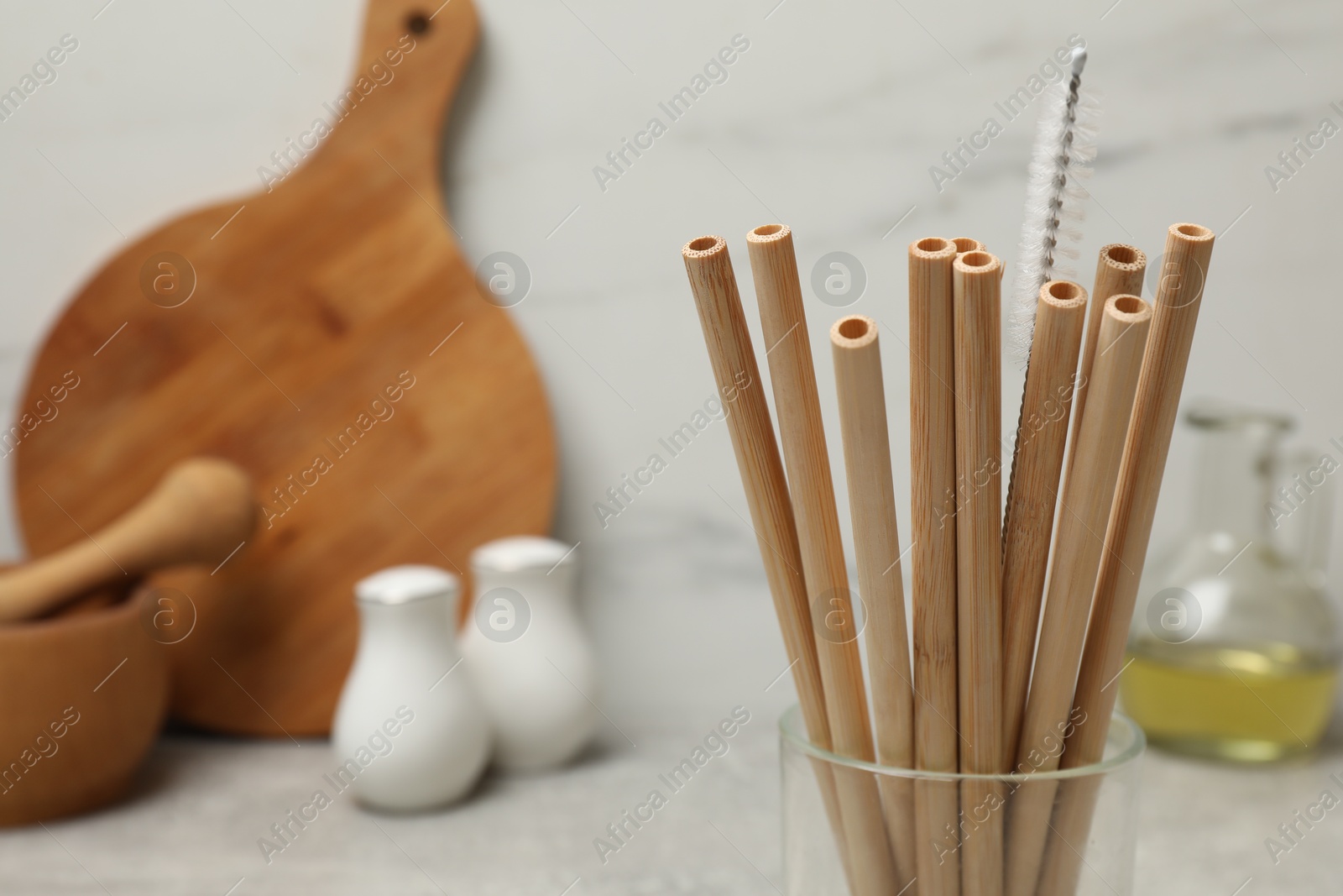 Photo of Bamboo drinking straws and cleaning brush in glass in kitchen, closeup. Space for text