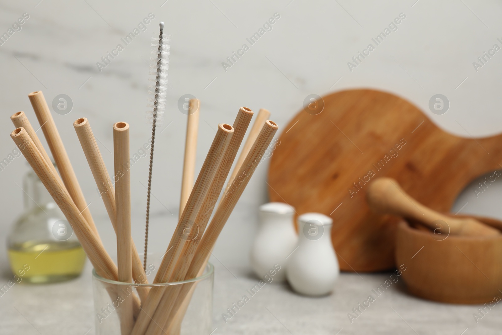 Photo of Bamboo drinking straws and cleaning brush in glass in kitchen, closeup. Space for text