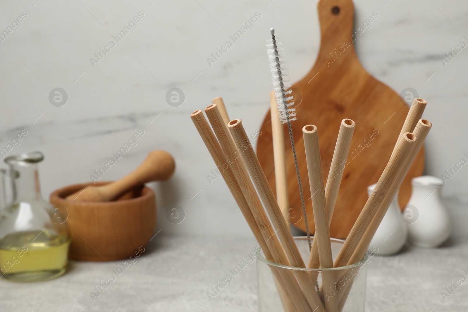 Photo of Bamboo drinking straws and cleaning brush in glass in kitchen, closeup. Space for text