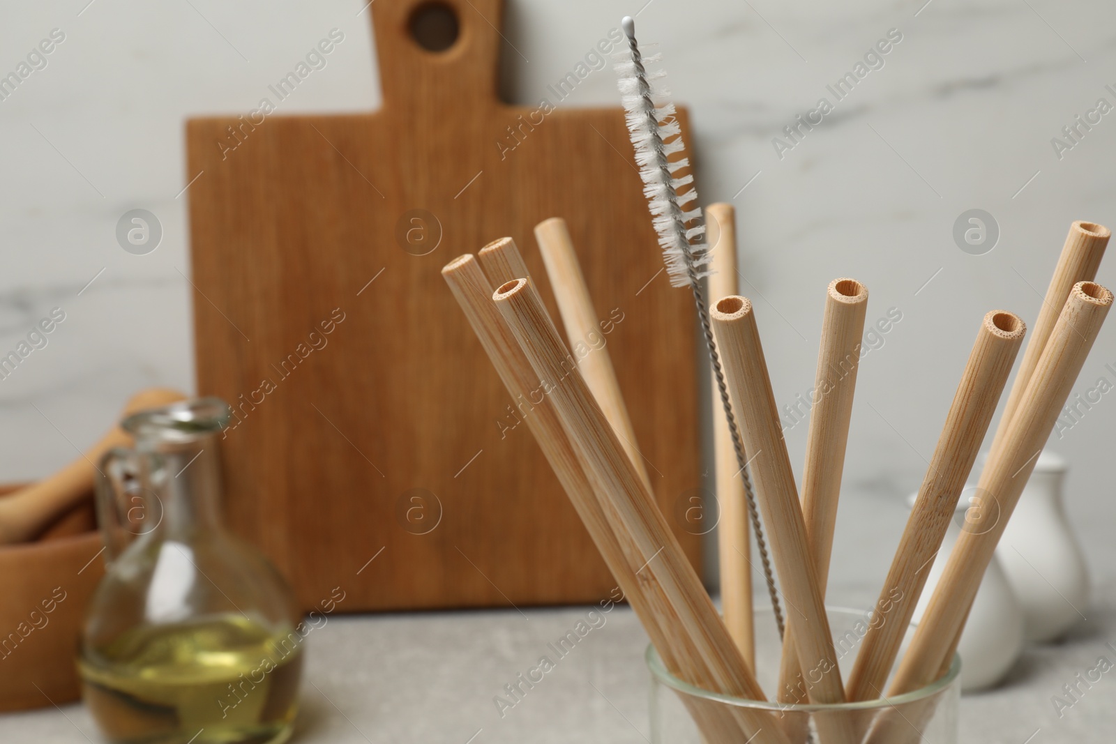 Photo of Bamboo drinking straws and cleaning brush in glass in kitchen, closeup. Space for text