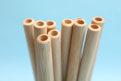 Photo of Bamboo drinking straws on light blue background, closeup