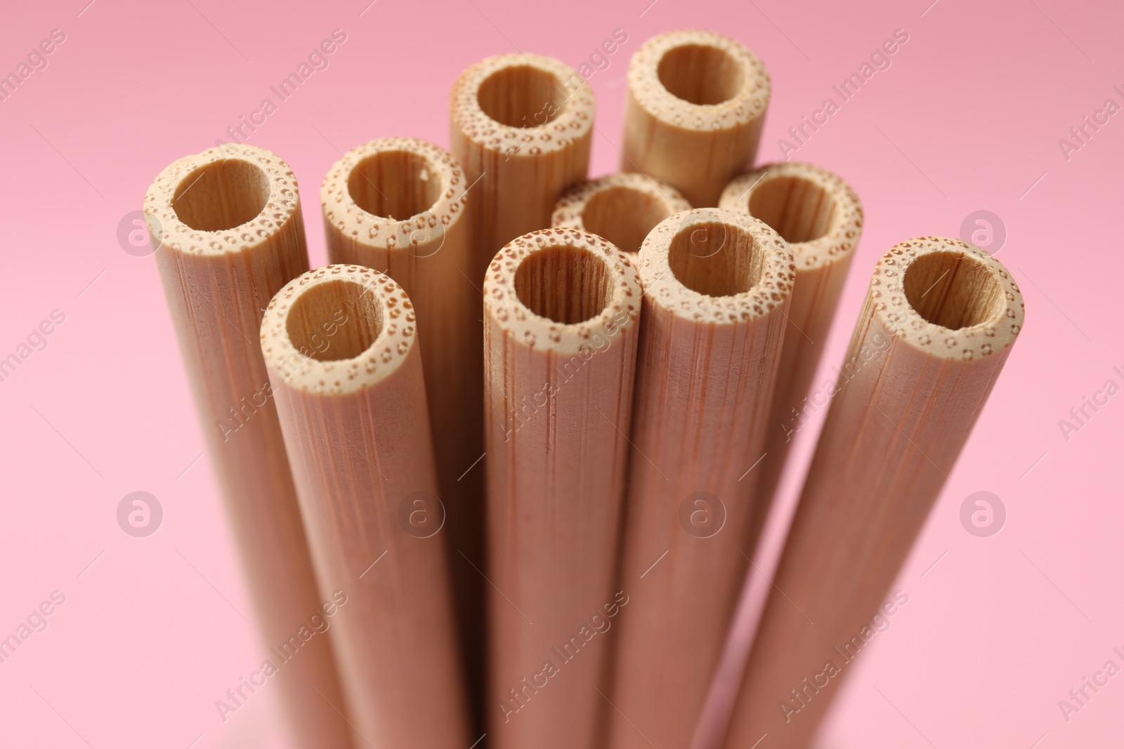 Photo of Bamboo drinking straws on pink background, closeup