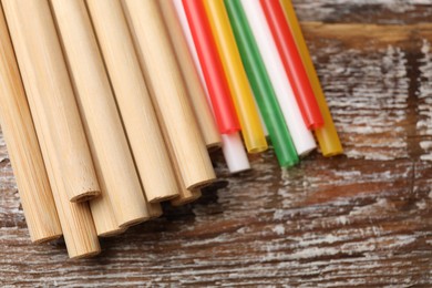 Photo of Different drinking straws on wooden table, closeup