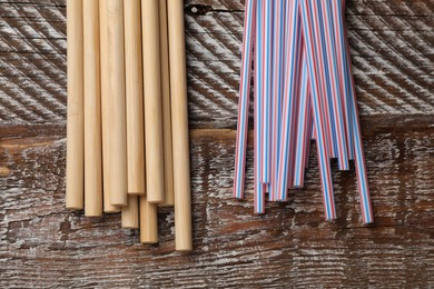 Photo of Different drinking straws on wooden table, flat lay