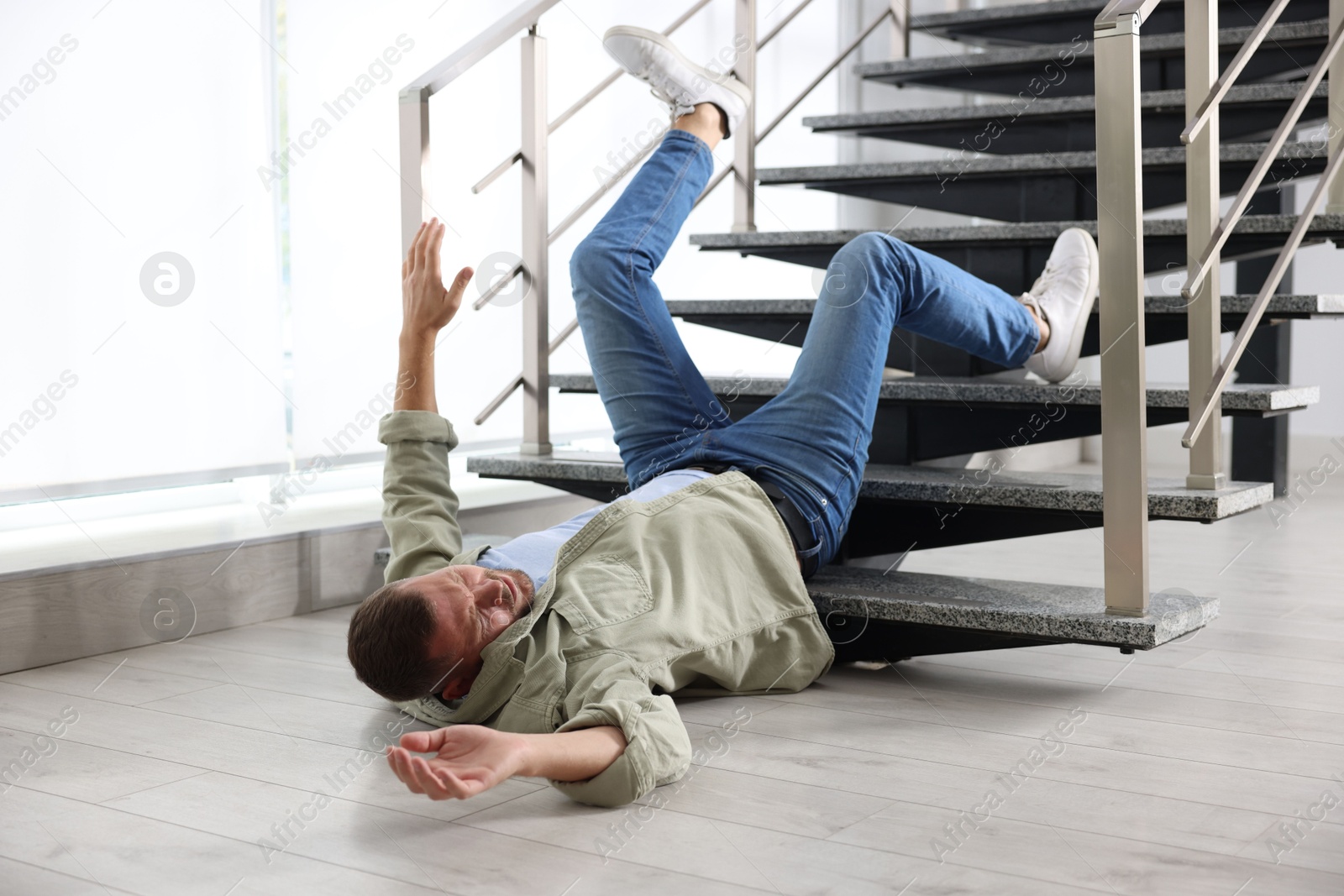 Photo of Injured man on floor in building after fall from stairs. Dangerous accident