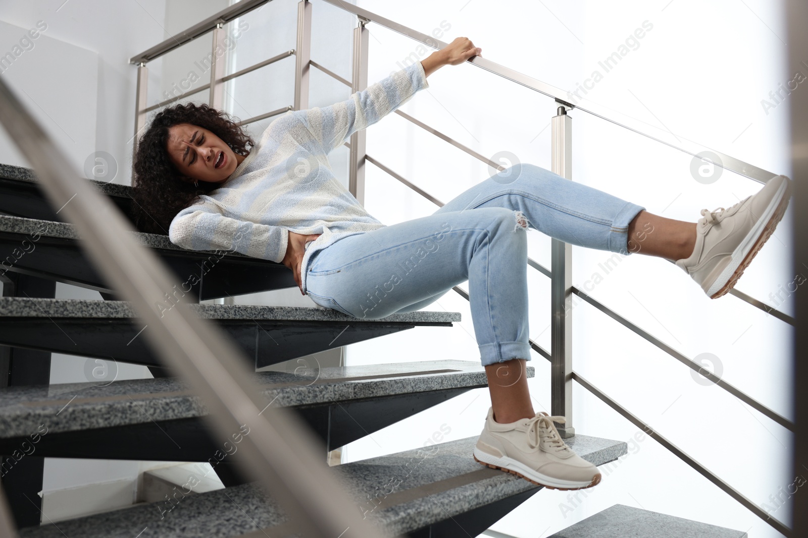 Photo of Injured woman on stairs in building after fall. Dangerous accident