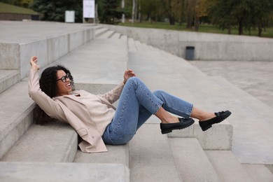 Photo of Injured woman on stairs outdoors after fall. Dangerous accident