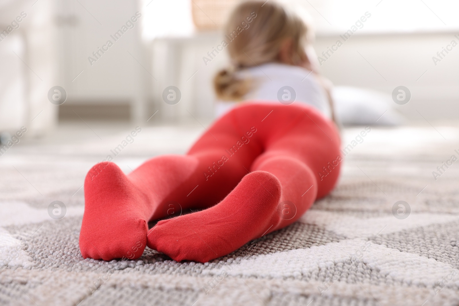 Photo of Child in red tights on floor at home, selective focus