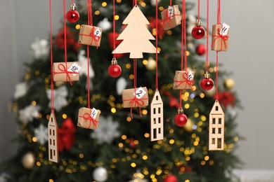 Photo of Handmade advent calendar with decor hanging near Christmas tree indoors