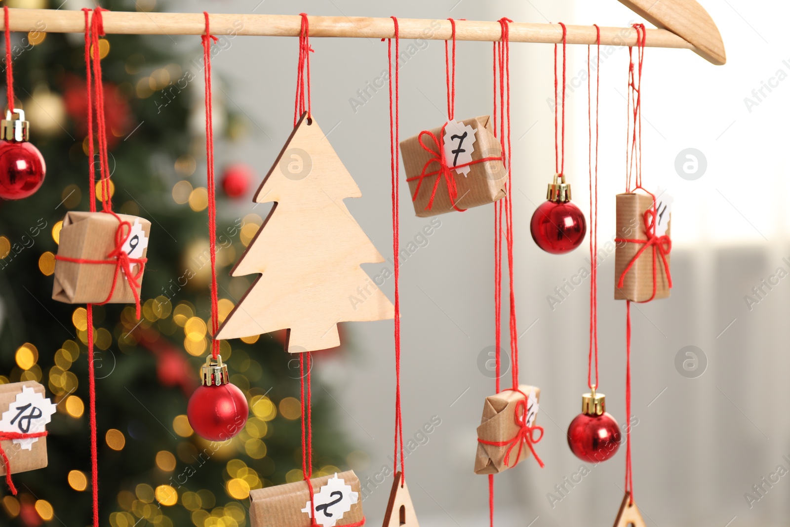 Photo of Handmade advent calendar with decor hanging near Christmas tree indoors