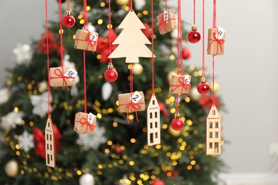 Photo of Handmade advent calendar with decor hanging near Christmas tree indoors