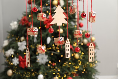 Photo of Handmade advent calendar with decor hanging near Christmas tree indoors