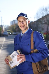 Photo of Happy postman with parcels outdoors. Mail service