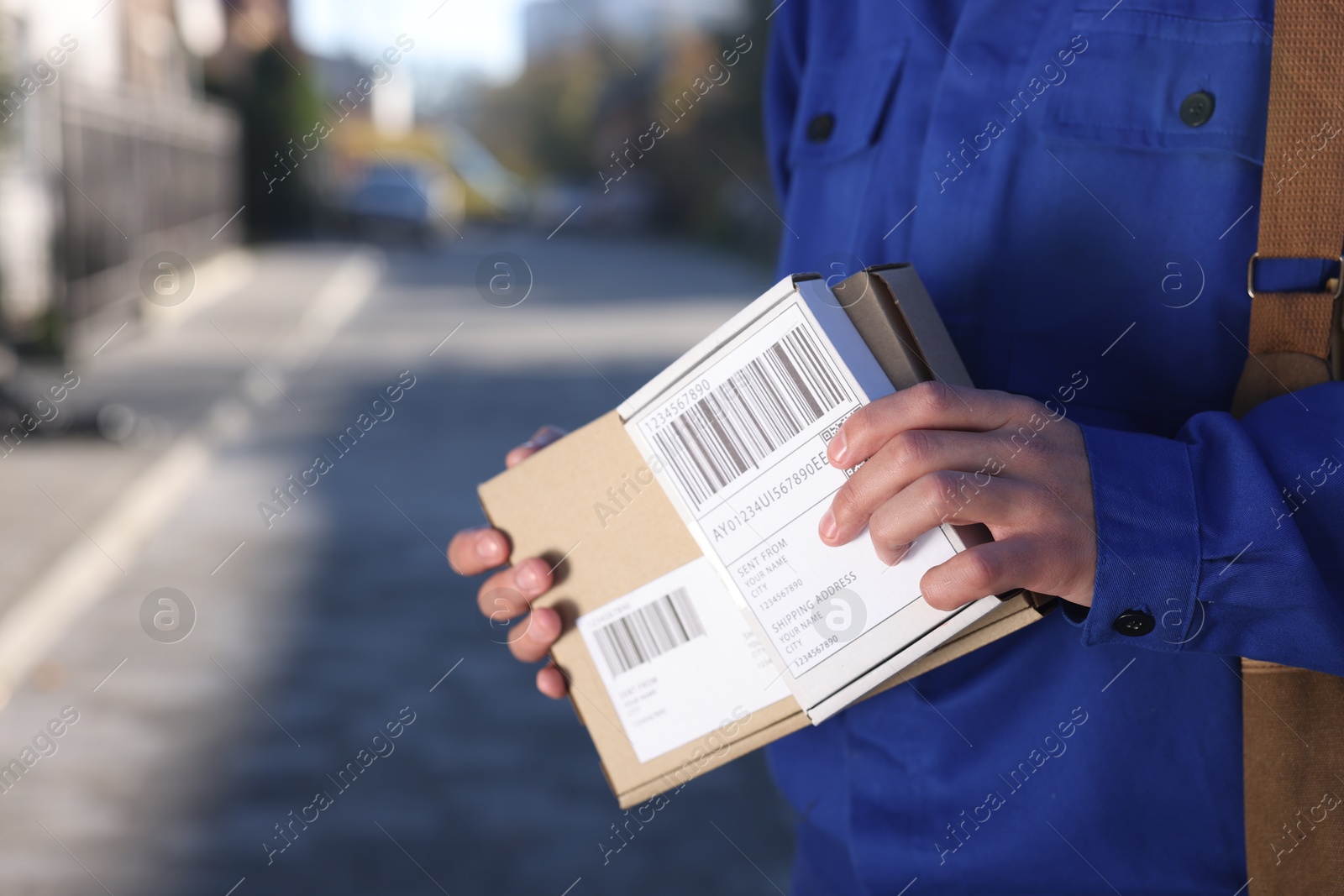 Photo of Postman with parcels outdoors, closeup. Mail service