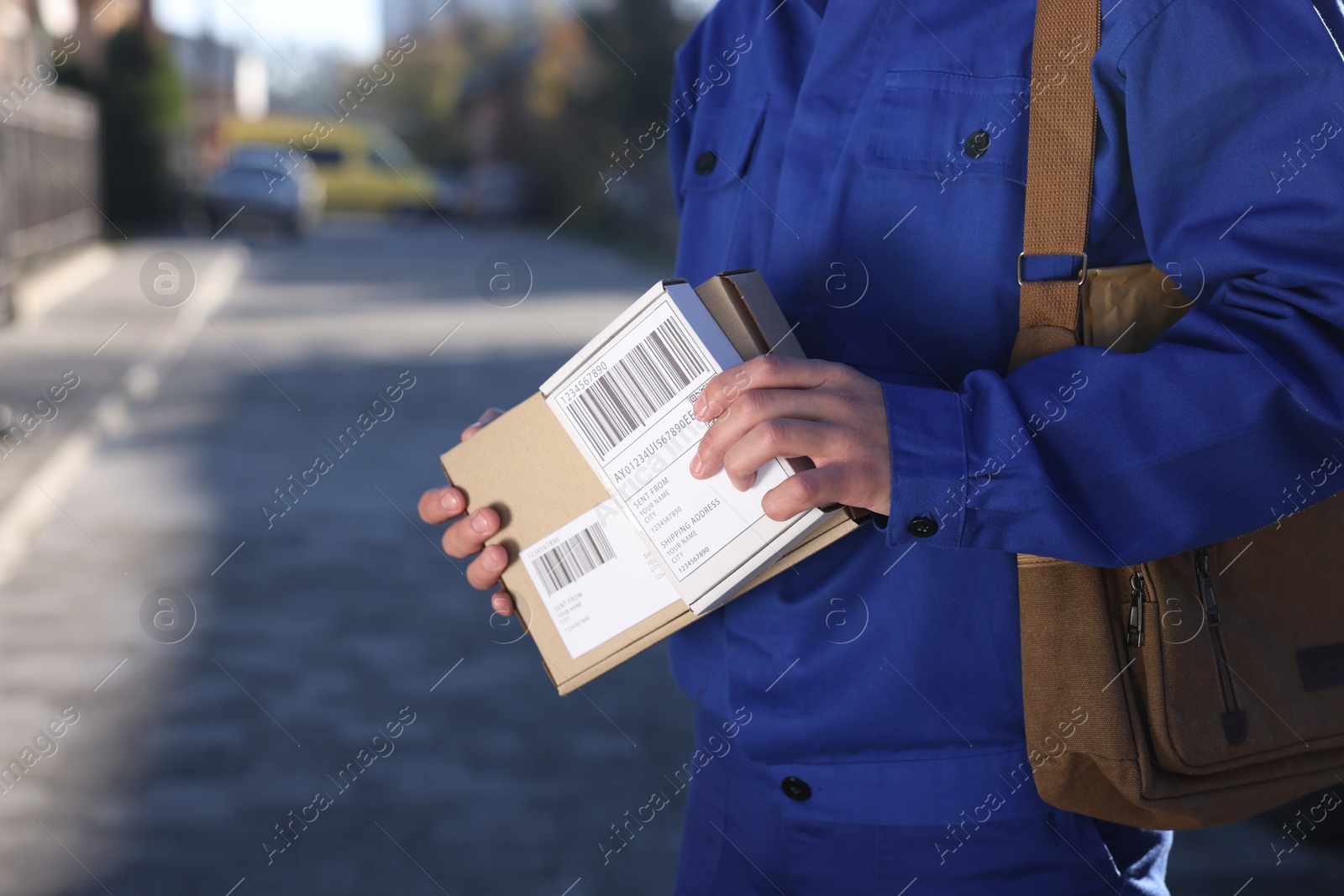 Photo of Postman with parcels outdoors, closeup. Mail service