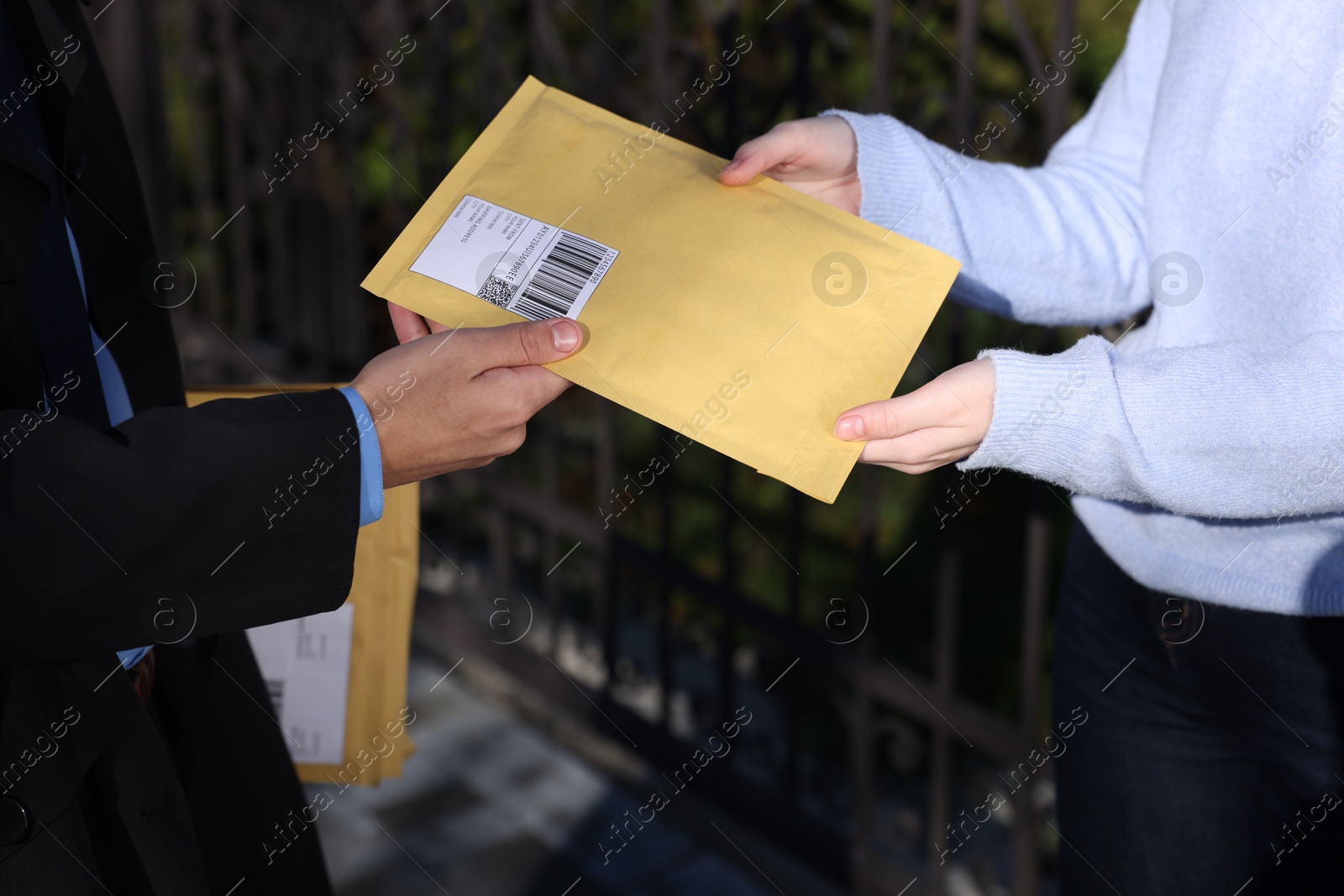 Photo of Postman giving parcel to woman outdoors, closeup