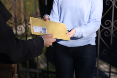 Photo of Postman giving parcel to woman outdoors, closeup