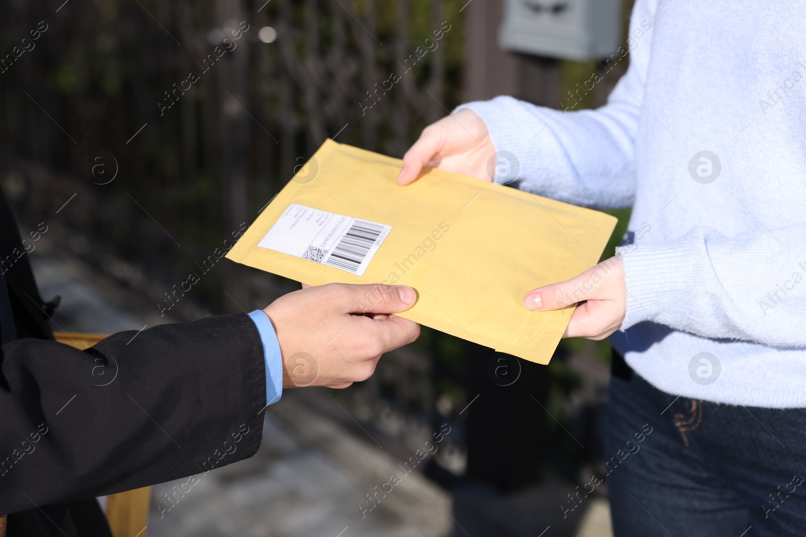 Photo of Postman giving parcel to woman outdoors, closeup