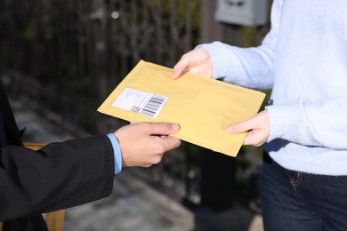 Photo of Postman giving parcel to woman outdoors, closeup