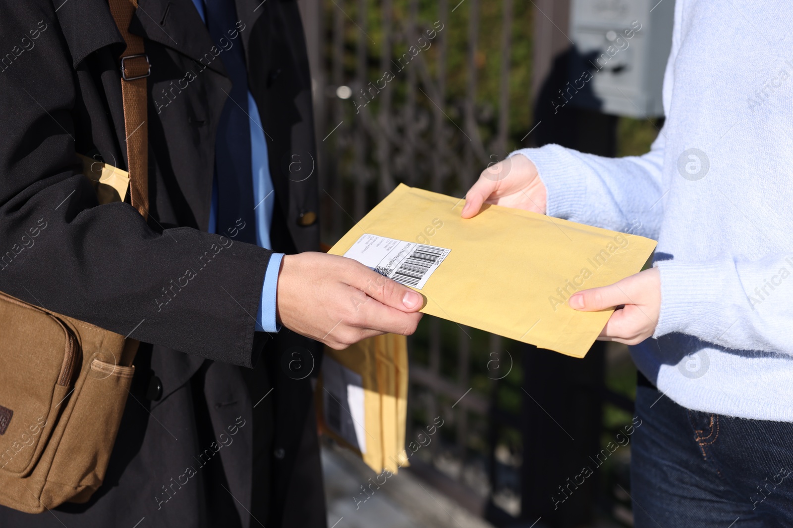 Photo of Postman giving parcel to woman outdoors, closeup