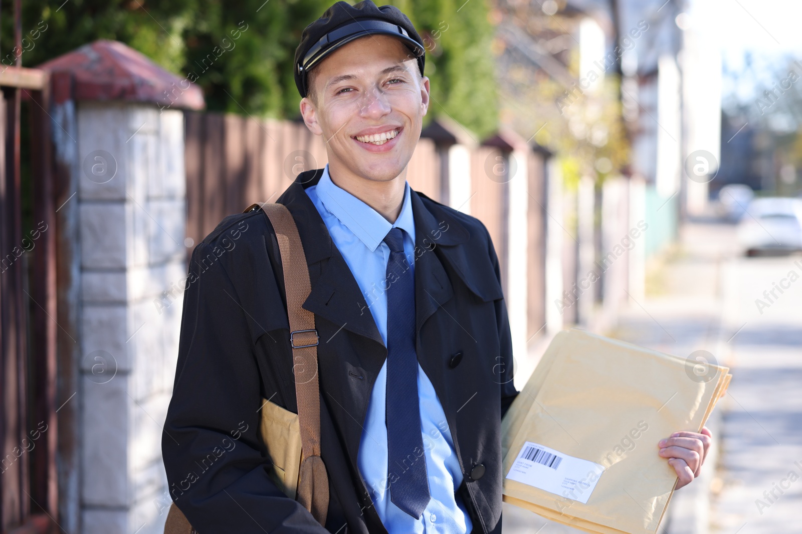 Photo of Happy postman with parcels outdoors. Mail service