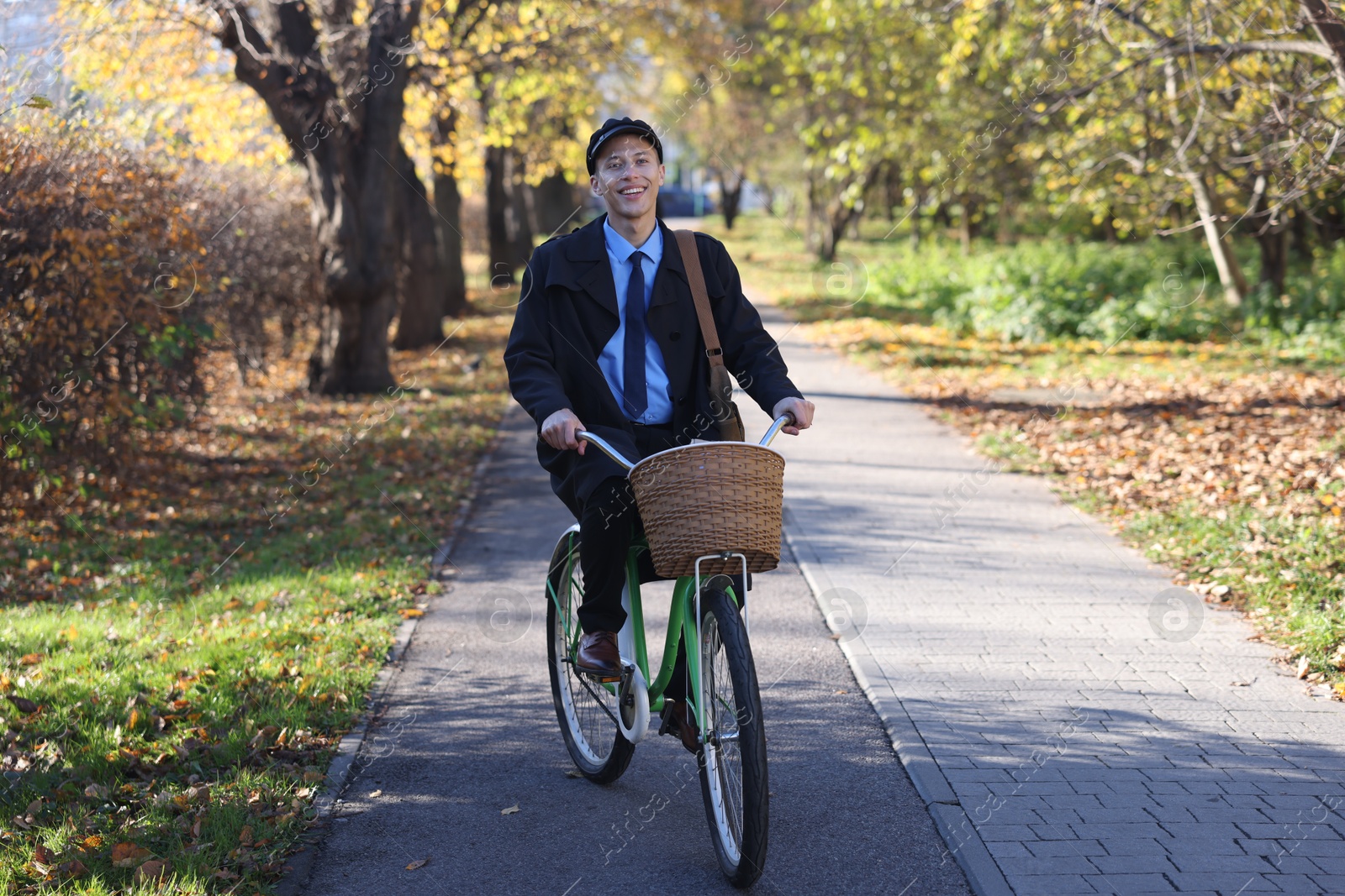 Photo of Happy mailman on bicycle outdoors. Postal service