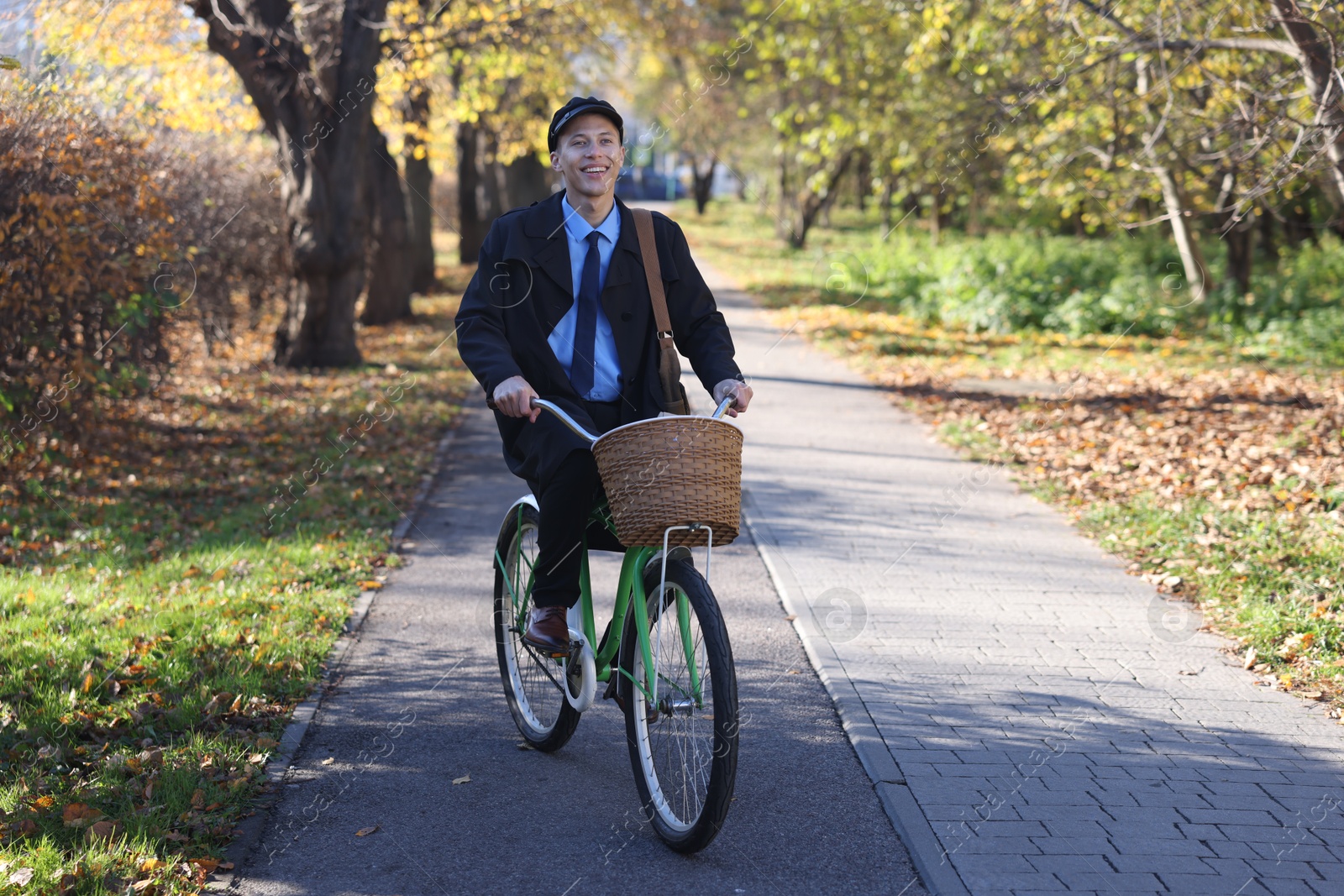 Photo of Happy mailman on bicycle outdoors. Postal service