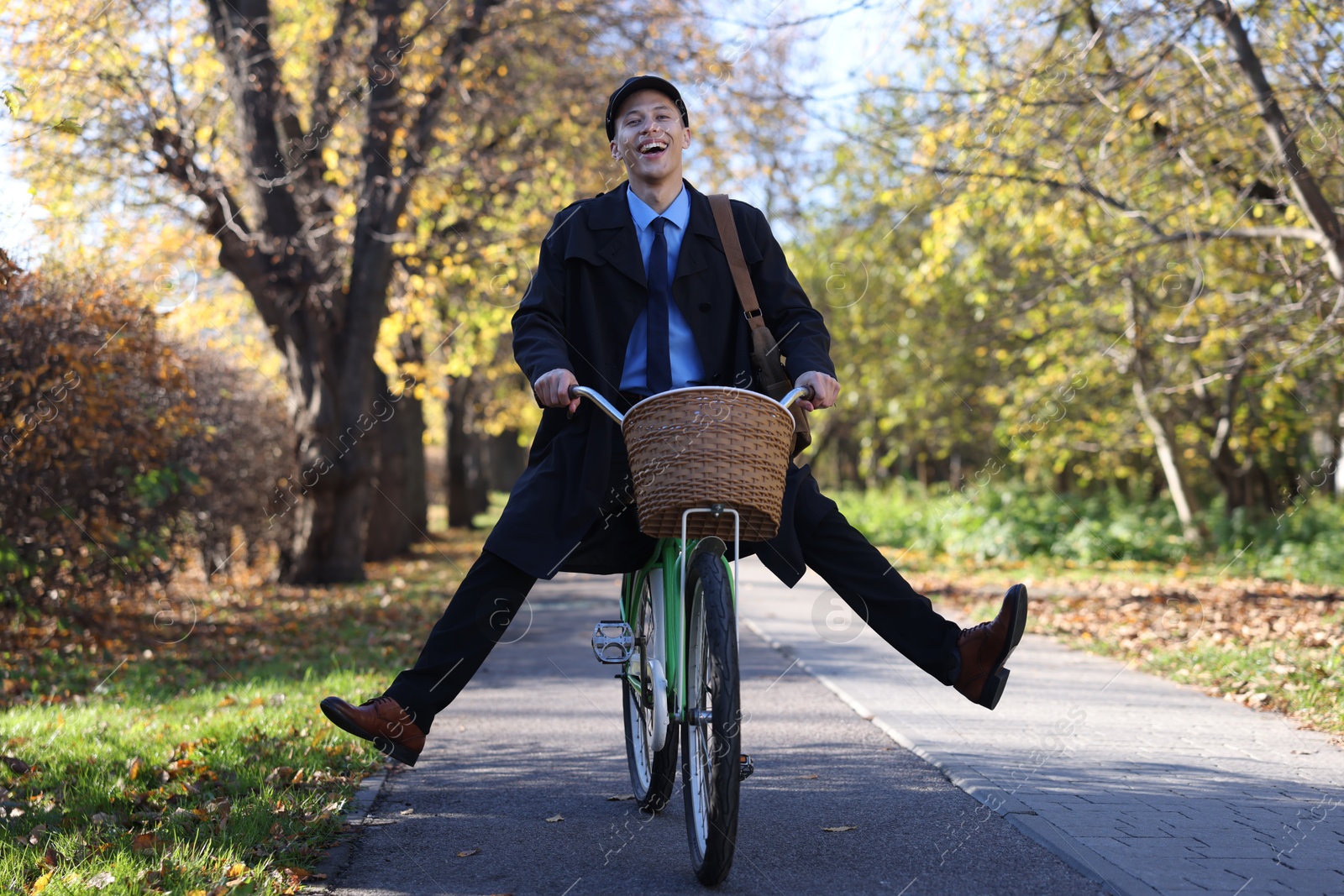 Photo of Happy mailman on bicycle outdoors. Postal service