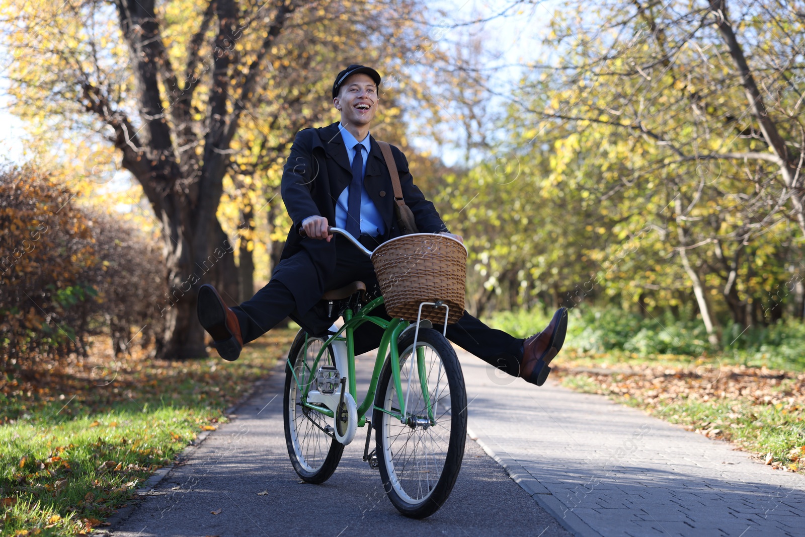 Photo of Happy mailman on bicycle outdoors. Postal service