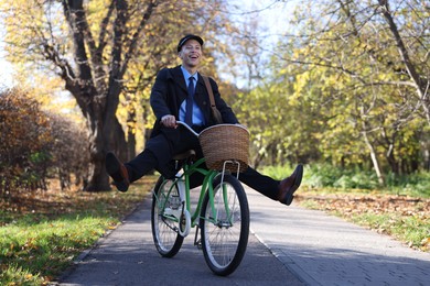 Photo of Happy mailman on bicycle outdoors. Postal service