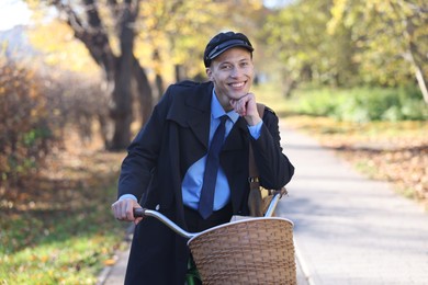 Photo of Happy mailman with bicycle outdoors. Postal service