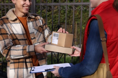 Photo of Postwoman giving parcels to man outdoors, closeup