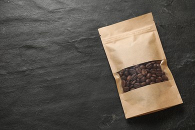 Paper pouch bag with coffee beans on black table, top view. Space for text