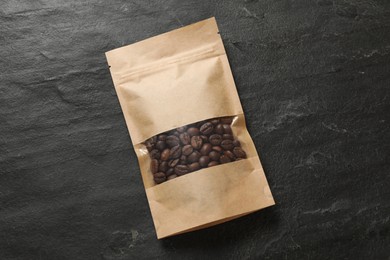 Photo of Paper pouch bag with coffee beans on black table, top view