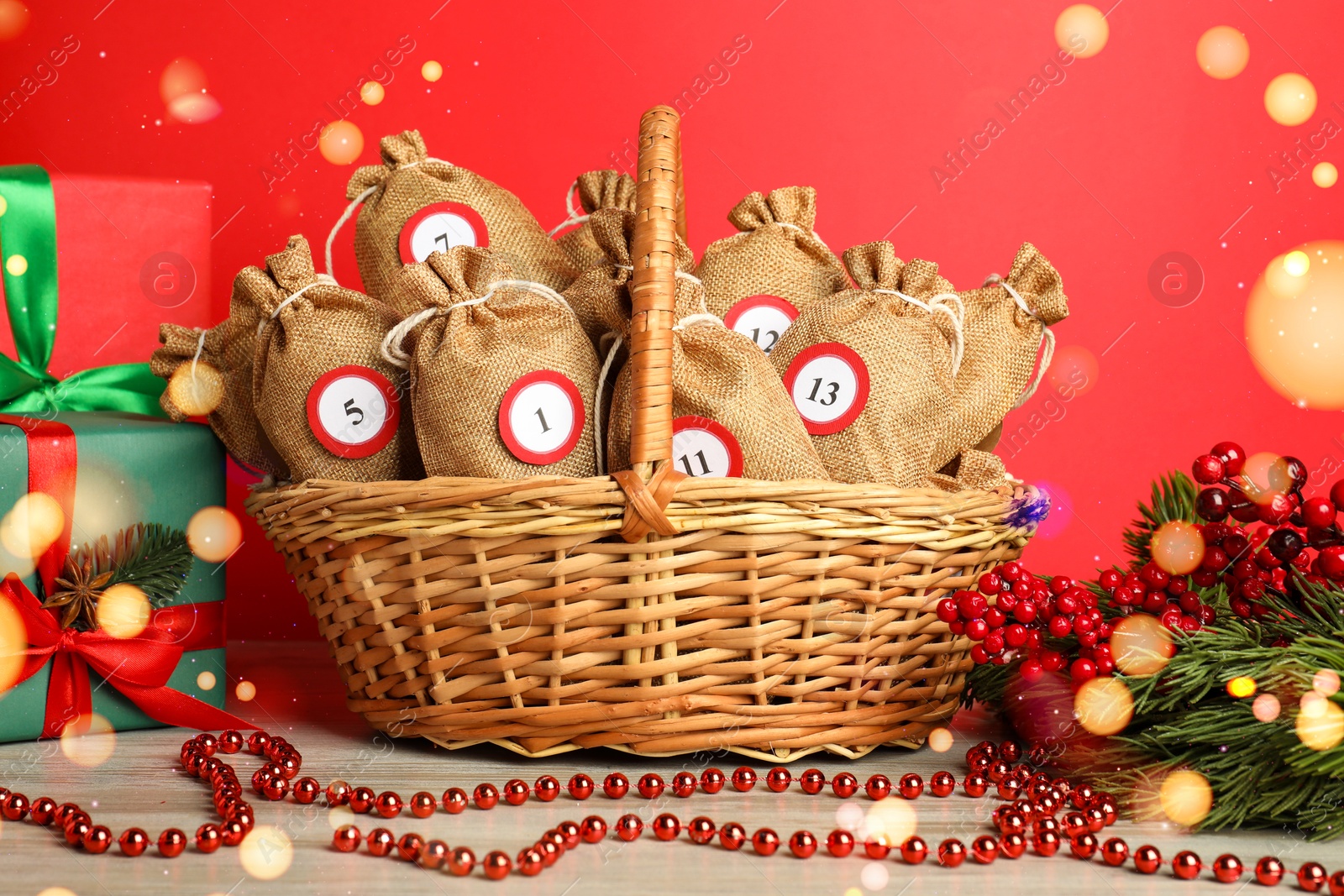 Photo of Christmas advent calendar with gifts in wicker basket and decor on wooden table