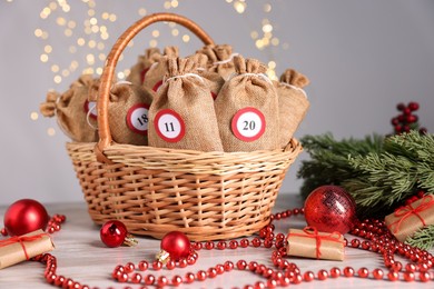 Photo of Christmas advent calendar with gifts in wicker basket and decor on wooden table against blurred lights