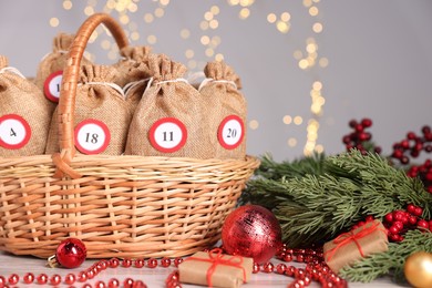 Photo of Christmas advent calendar with gifts in wicker basket and decor on table against blurred lights, closeup